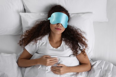 African American woman with sleeping mask in bed, top view