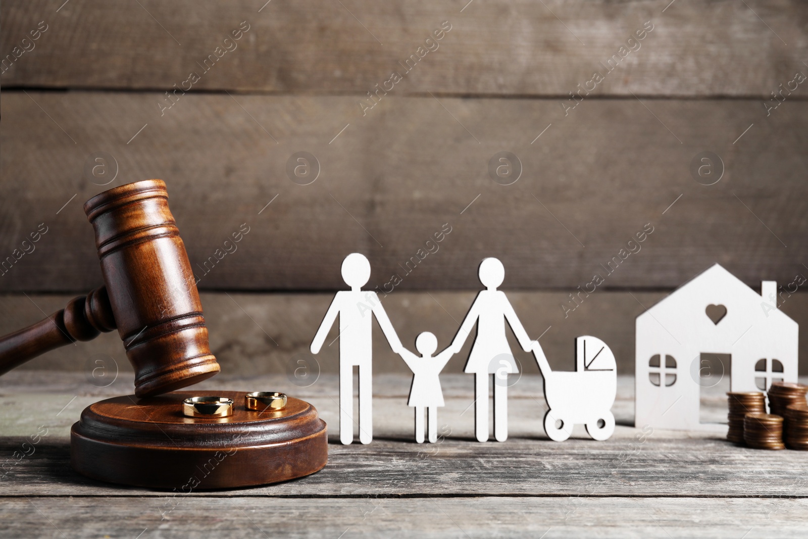 Photo of Divorce concept. Gavel, wedding rings and paper cutout of family on wooden table