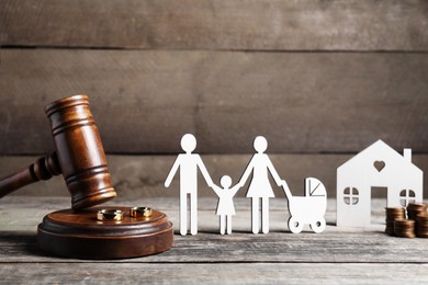 Divorce concept. Gavel, wedding rings and paper cutout of family on wooden table