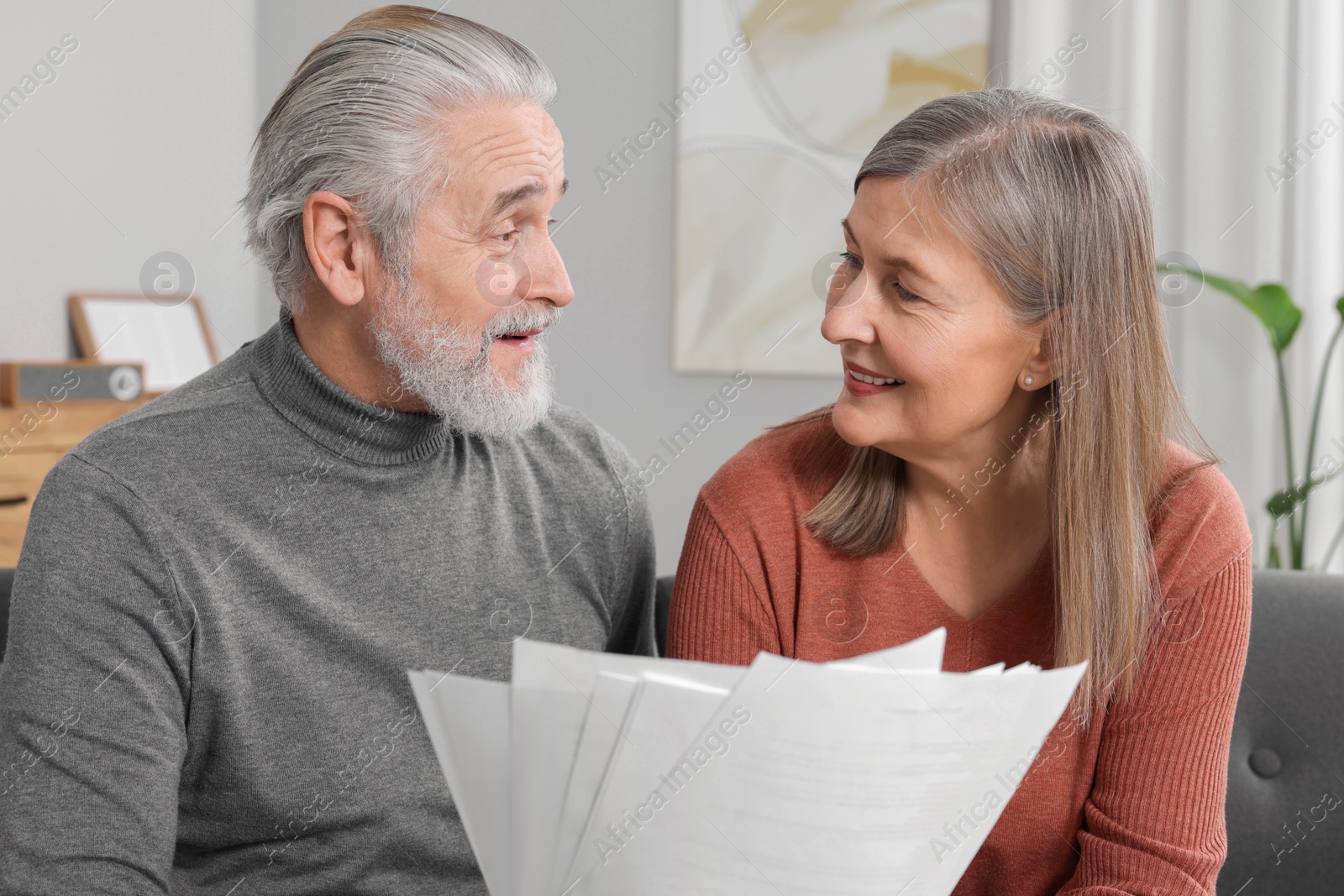 Photo of Elderly couple with papers discussing pension plan in room