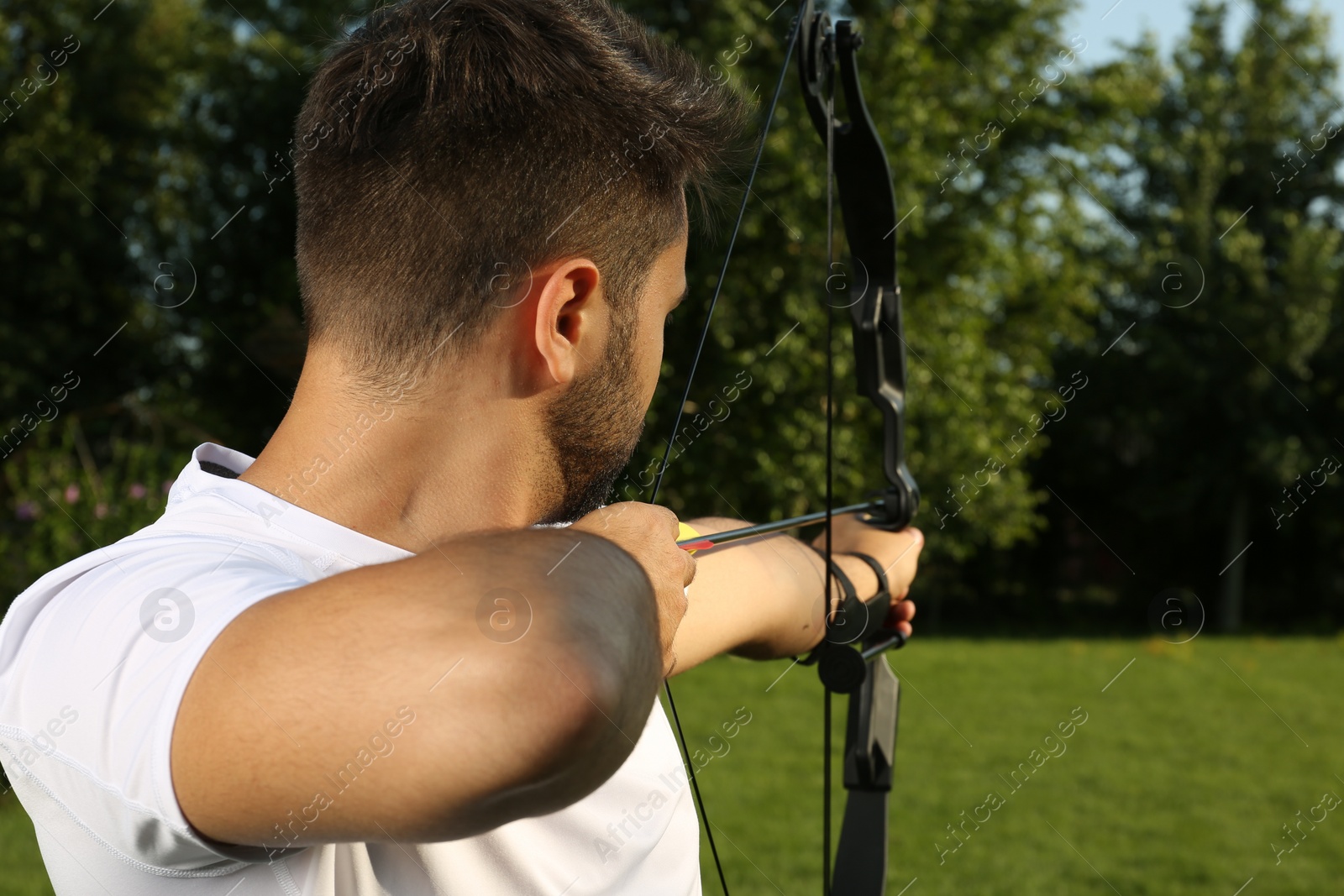 Photo of Man with bow and arrow practicing archery in park