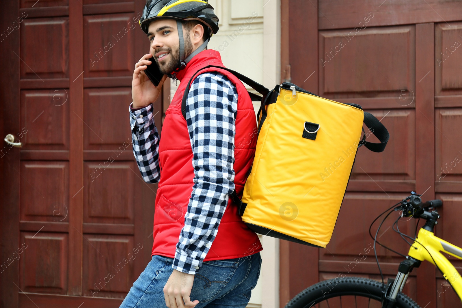 Photo of Courier with thermo bag and mobile phone near customer's house. Food delivery service