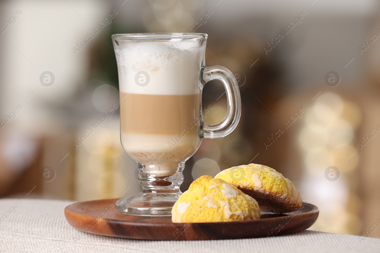 Photo of Aromatic latte macchiato in glass and cookies on white table against blurred background, closeup