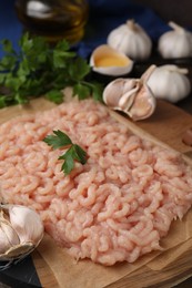 Fresh raw minced meat, parsley and garlic on wooden table, closeup