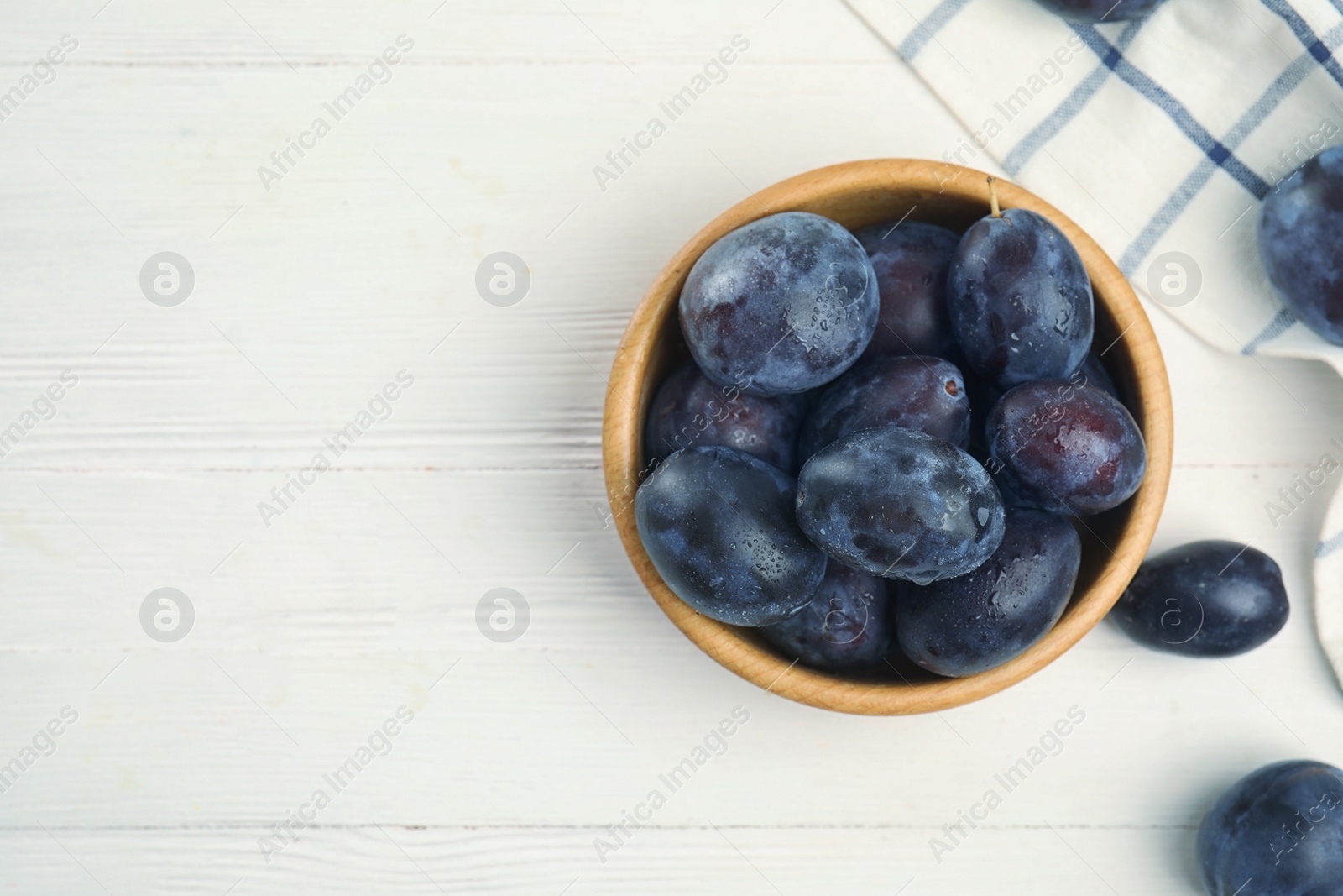 Photo of Delicious ripe plums on white wooden table, flat lay. Space for text