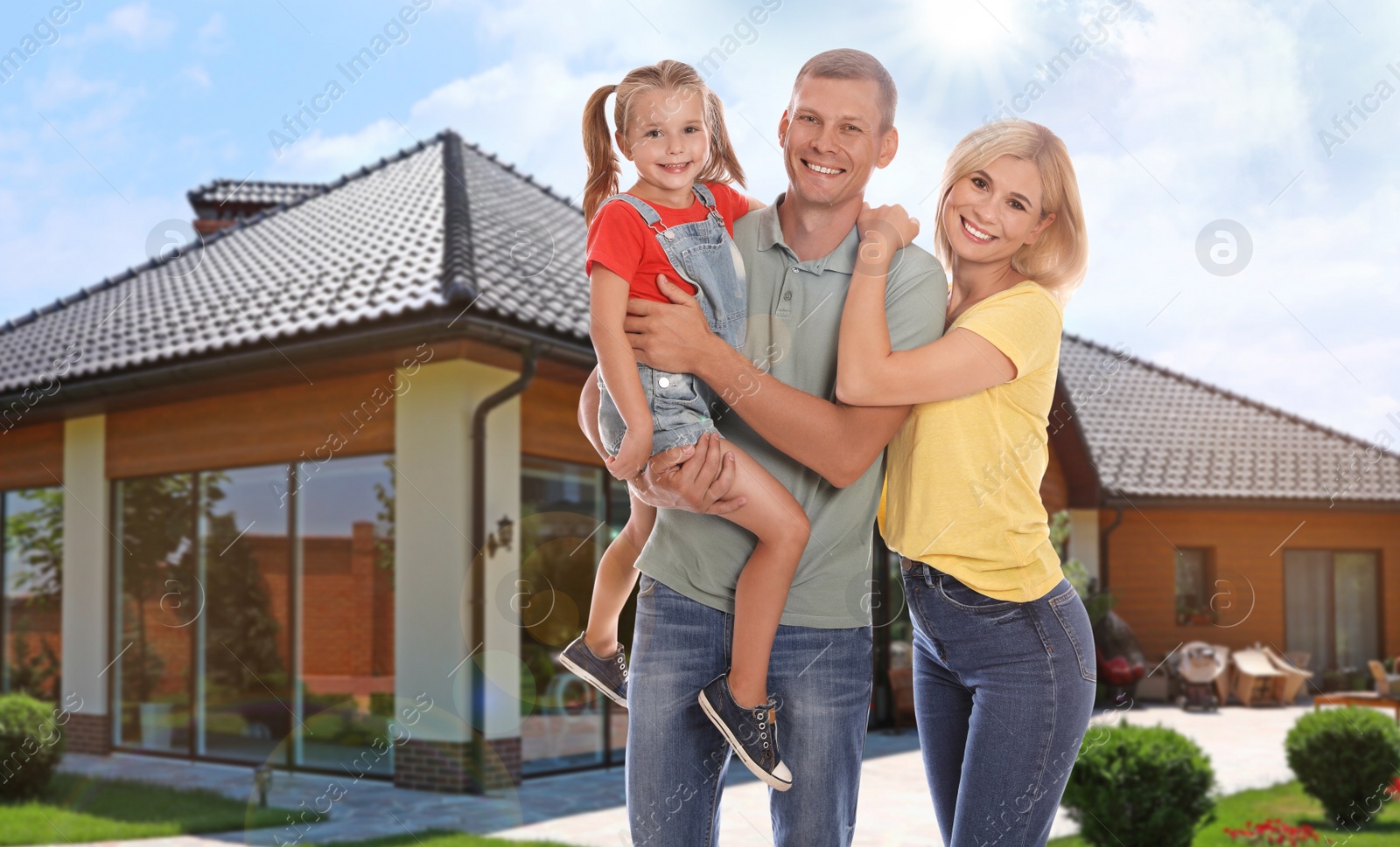 Image of Happy family standing in front of their house on sunny day 