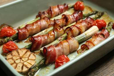 Photo of Oven baked asparagus wrapped with bacon in ceramic dish, closeup