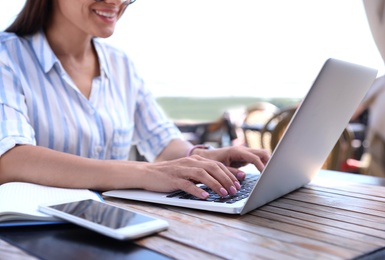 Photo of Woman using laptop at outdoor cafe, closeup
