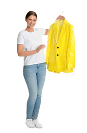 Photo of Young woman holding hanger with jacket in plastic bag on white background. Dry-cleaning service