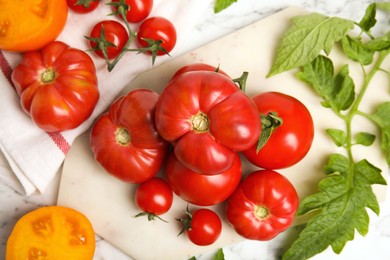 Photo of Flat lay composition with different ripe tomatoes and leaves on white marble table