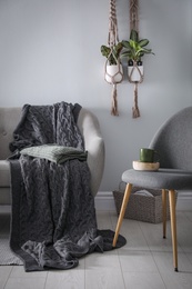 Photo of Soft knitted blanket on sofa in room. Home interior