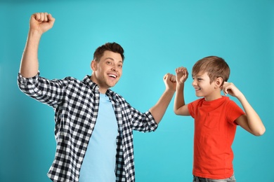 Portrait of emotional dad and his son on color background