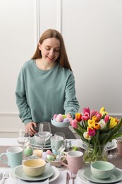 Woman setting table for festive Easter dinner at home