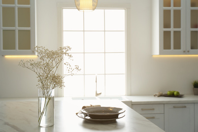 Photo of Beautiful plates and bouquet on table in kitchen