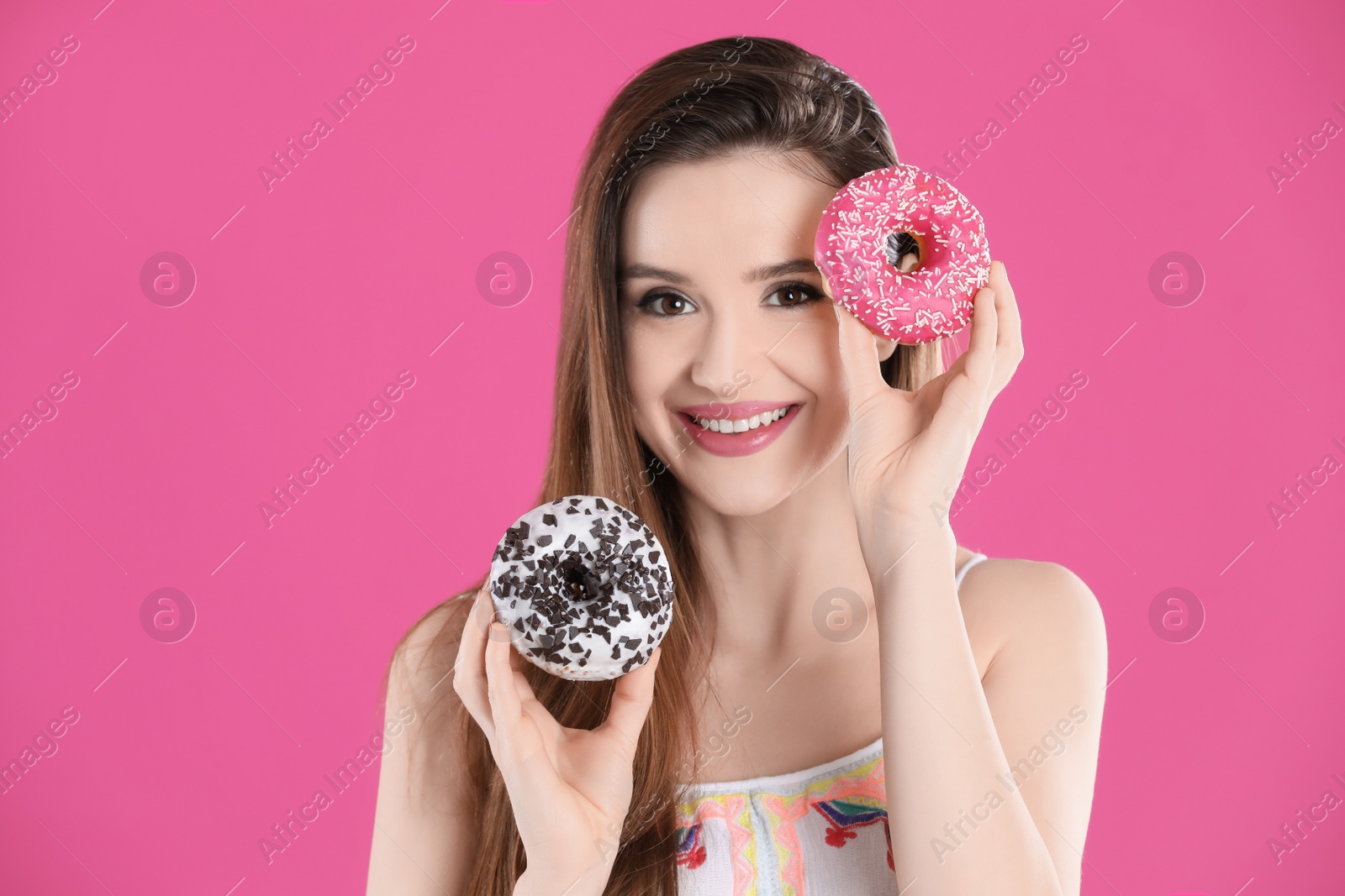 Photo of Beautiful young woman with donuts on pink background