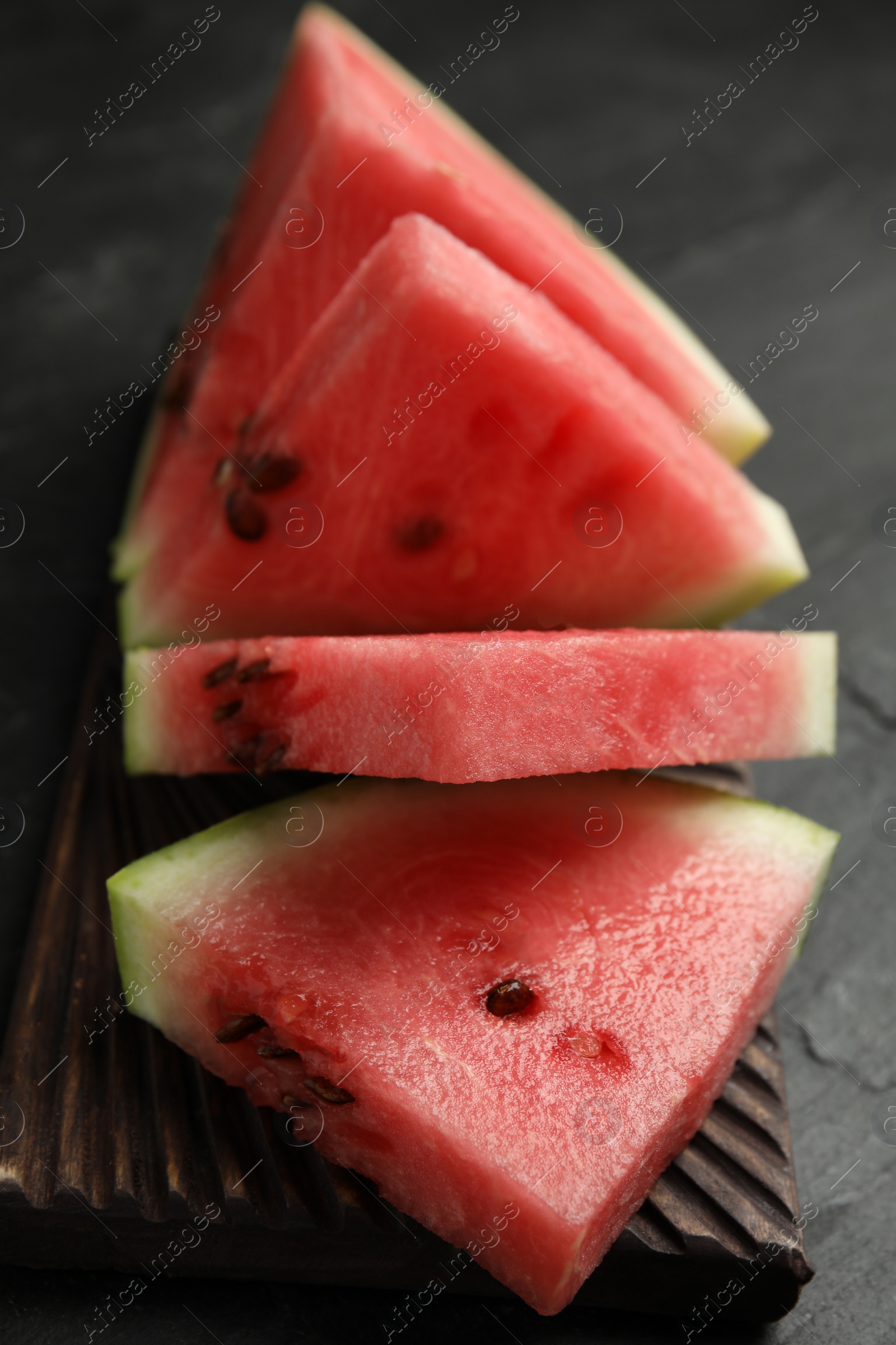 Photo of Cut ripe watermelon on black table, closeup