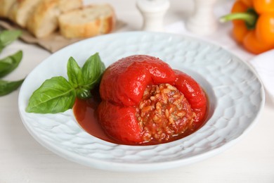 Photo of Delicious stuffed pepper with basil in bowl on white table, closeup