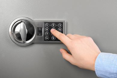 Man opening steel safe with electronic combination lock, closeup