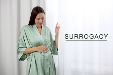 Surrogacy. Pregnant woman touching her belly near window indoors