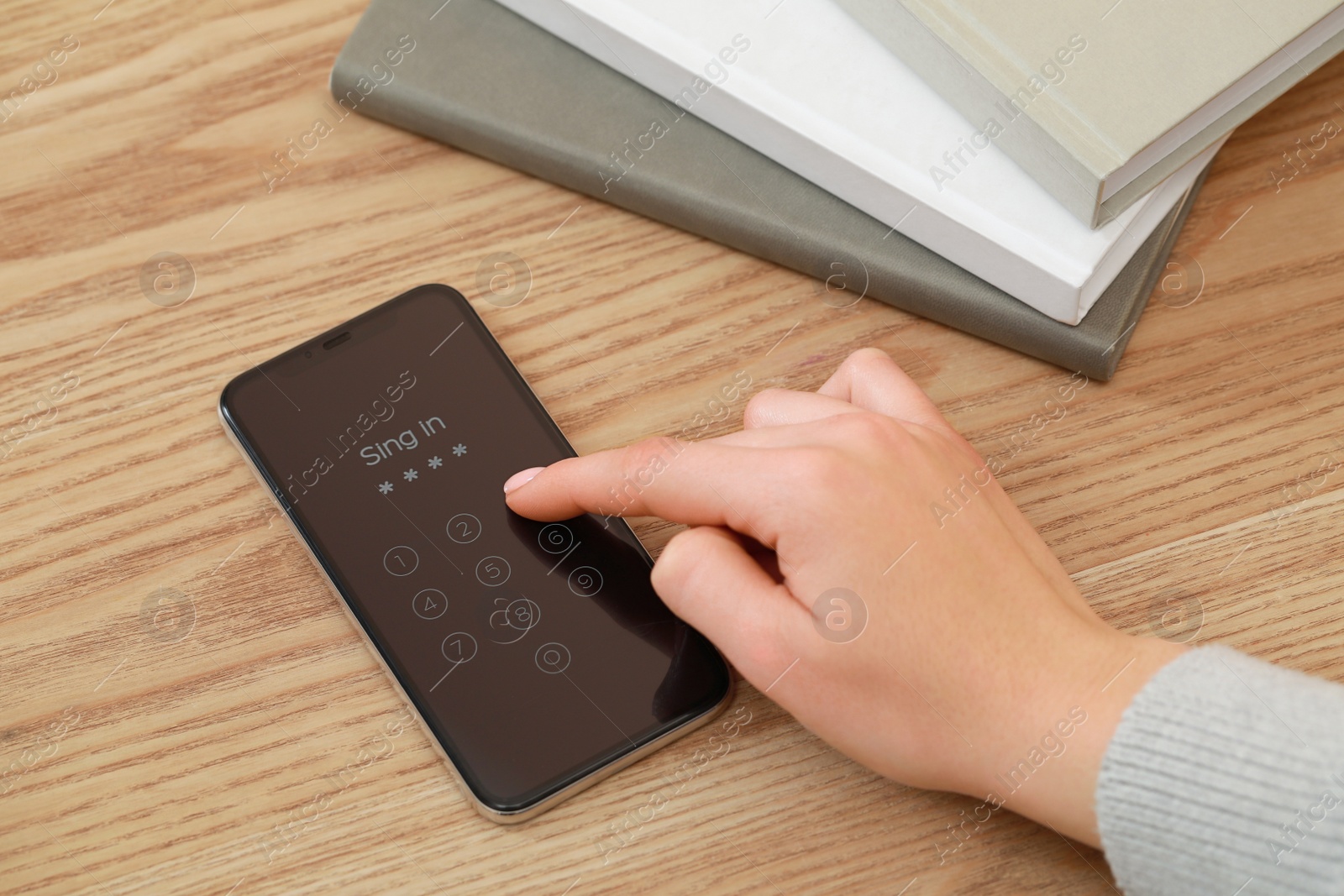 Photo of Woman unlocking smartphone with blocked screen at wooden table, closeup