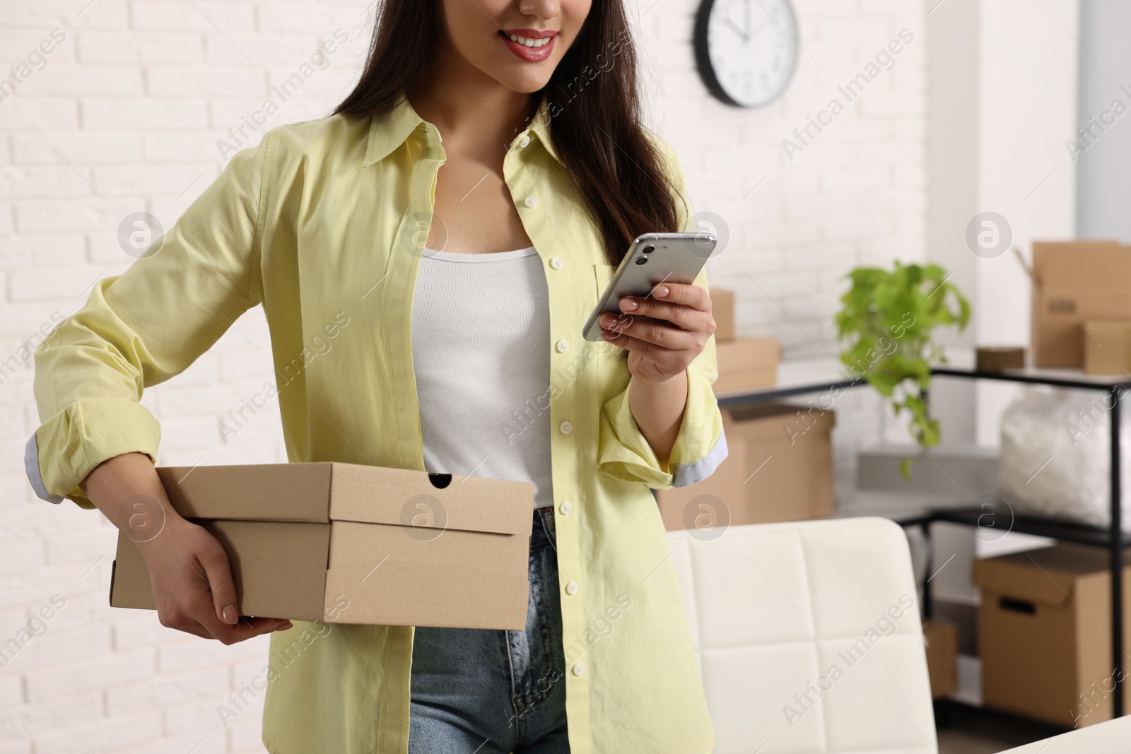 Photo of Seller with parcel and smartphone in office, closeup. Online store