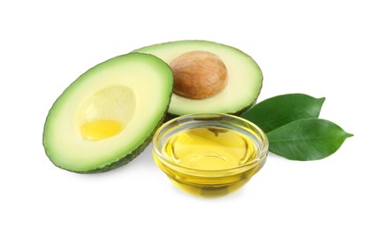 Photo of Bowl of oil and cut avocado on white background