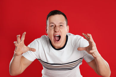 Emotional young man posing on red background