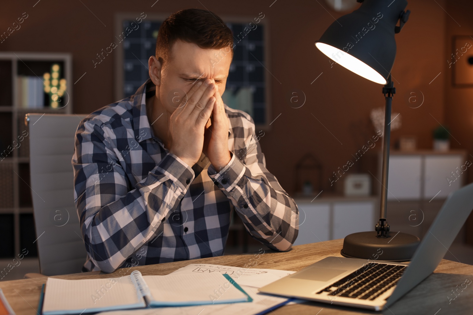 Photo of Overworked man with headache in office