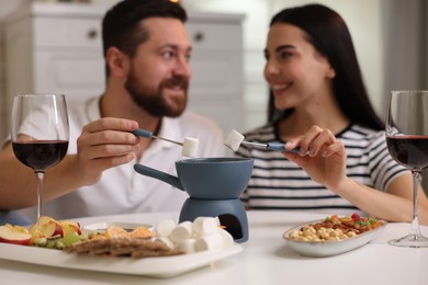 Photo of Affectionate couple enjoying fondue during romantic date at home, selective focus