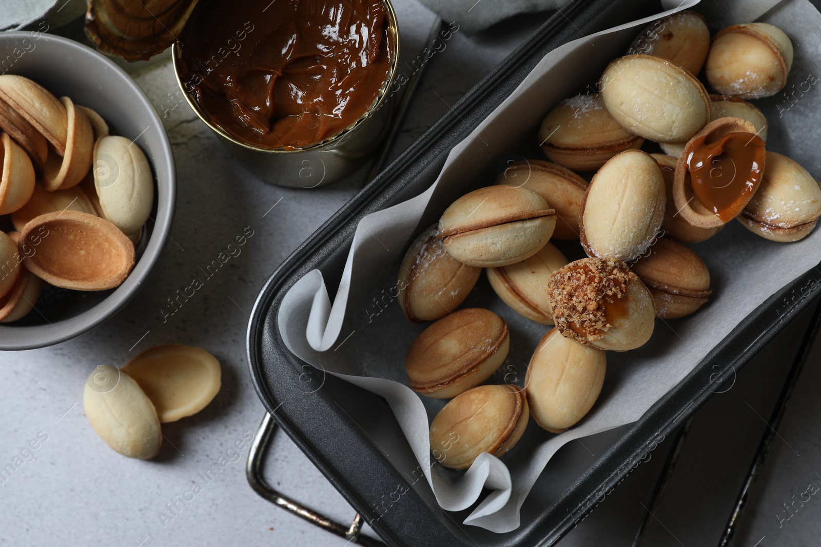 Photo of Delicious walnut shaped cookies with condensed milk on grey table, flat lay