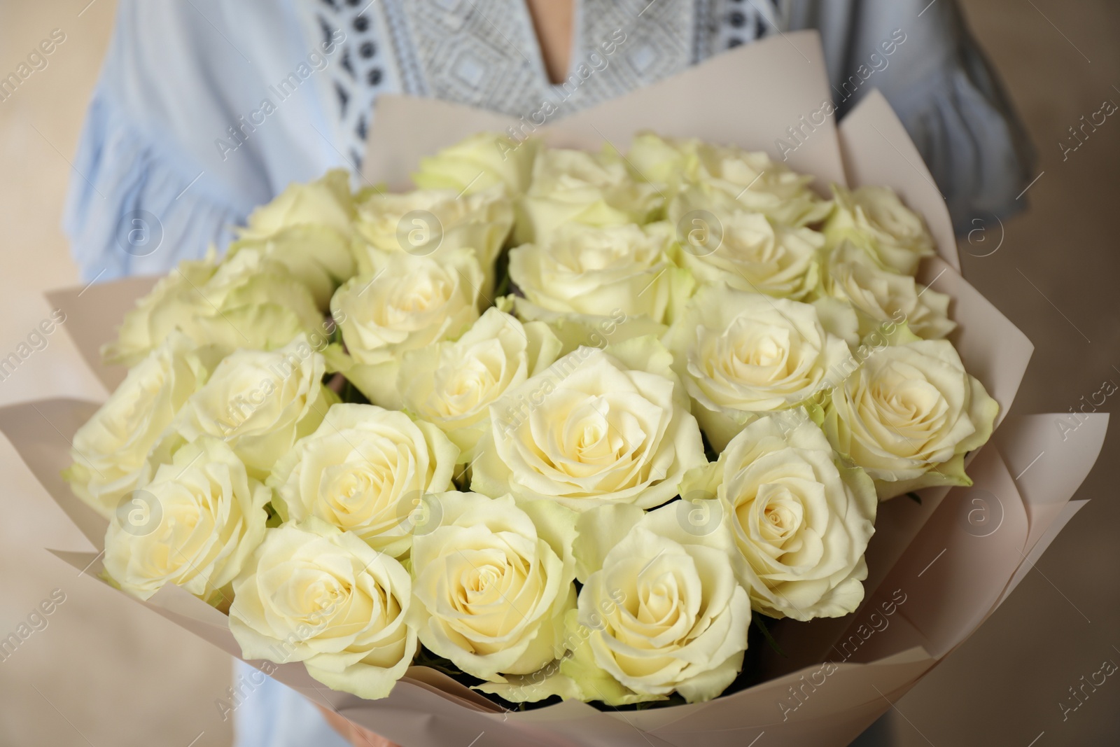 Photo of Woman holding luxury bouquet of fresh roses on light background, closeup