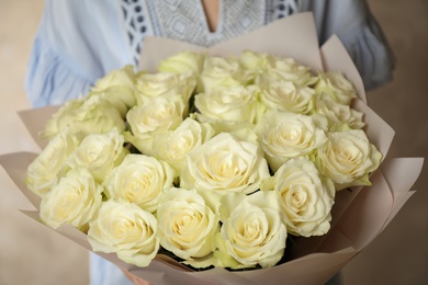 Woman holding luxury bouquet of fresh roses on light background, closeup