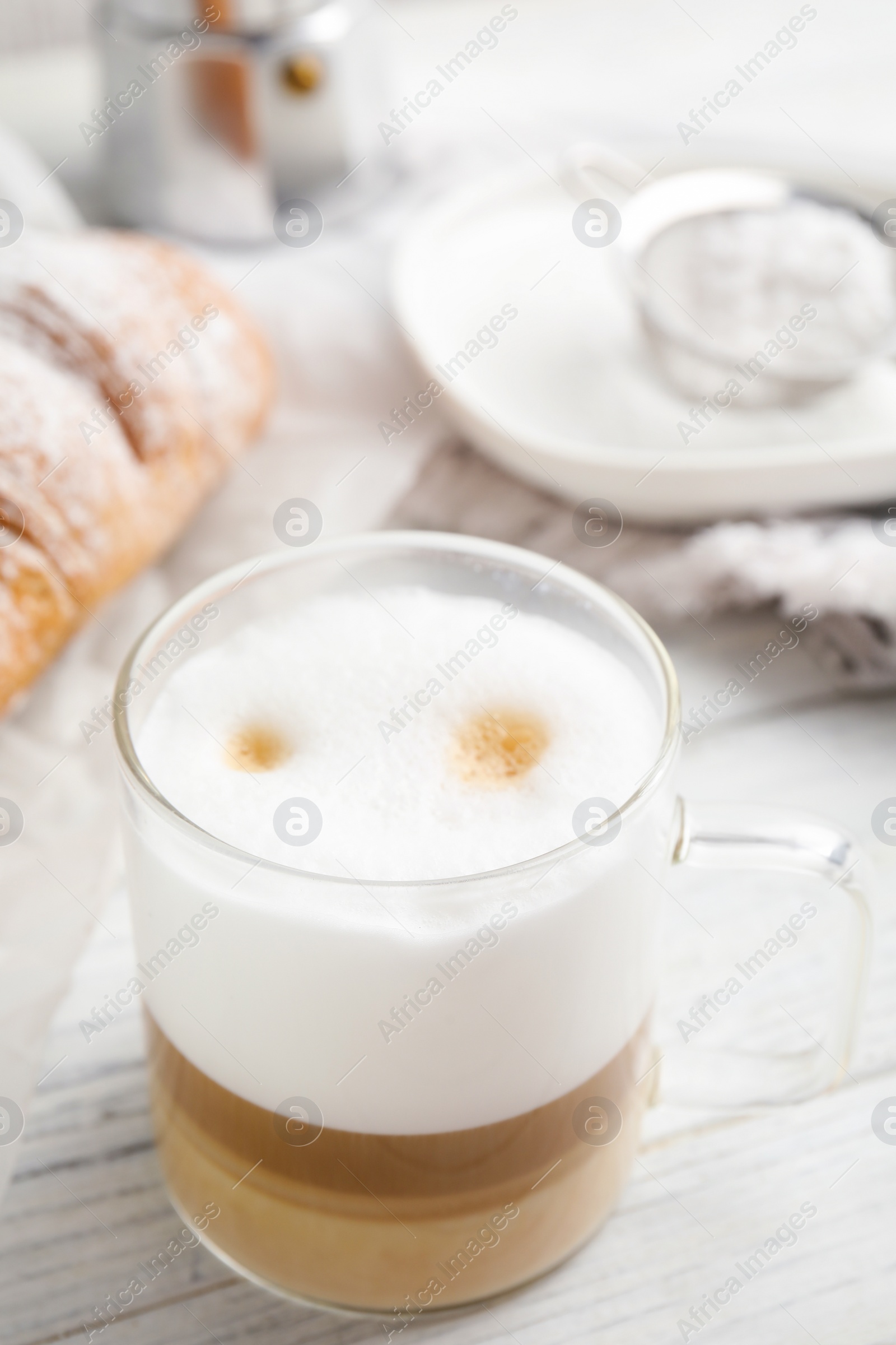 Photo of Delicious latte macchiato and croissant on white wooden table