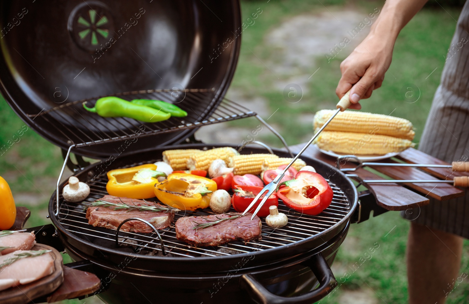 Photo of Man cooking food on barbecue grill outdoors, closeup