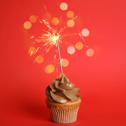 Image of Birthday cupcake with sparkler on red background