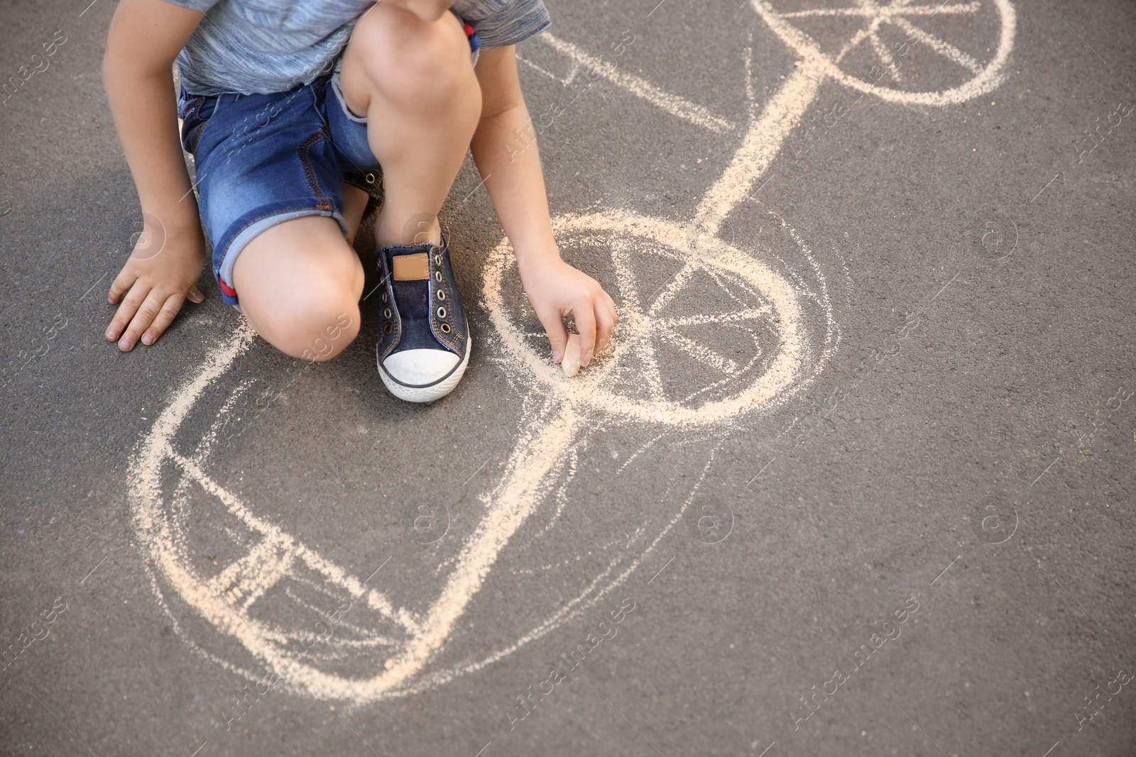 Photo of Little child drawing car with chalk on asphalt