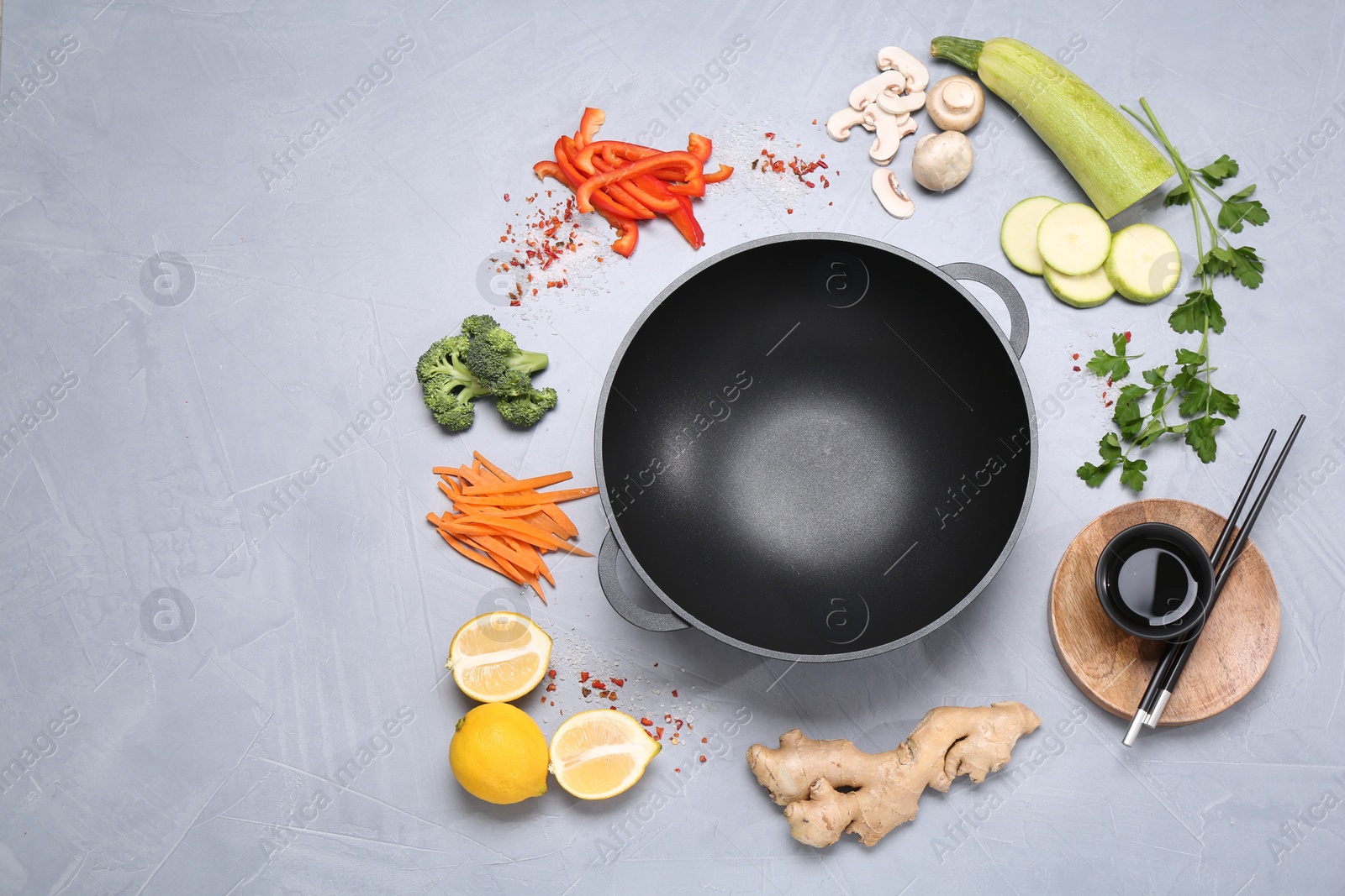 Photo of Wok, chopsticks and different products on grey table, flat lay. Space for text