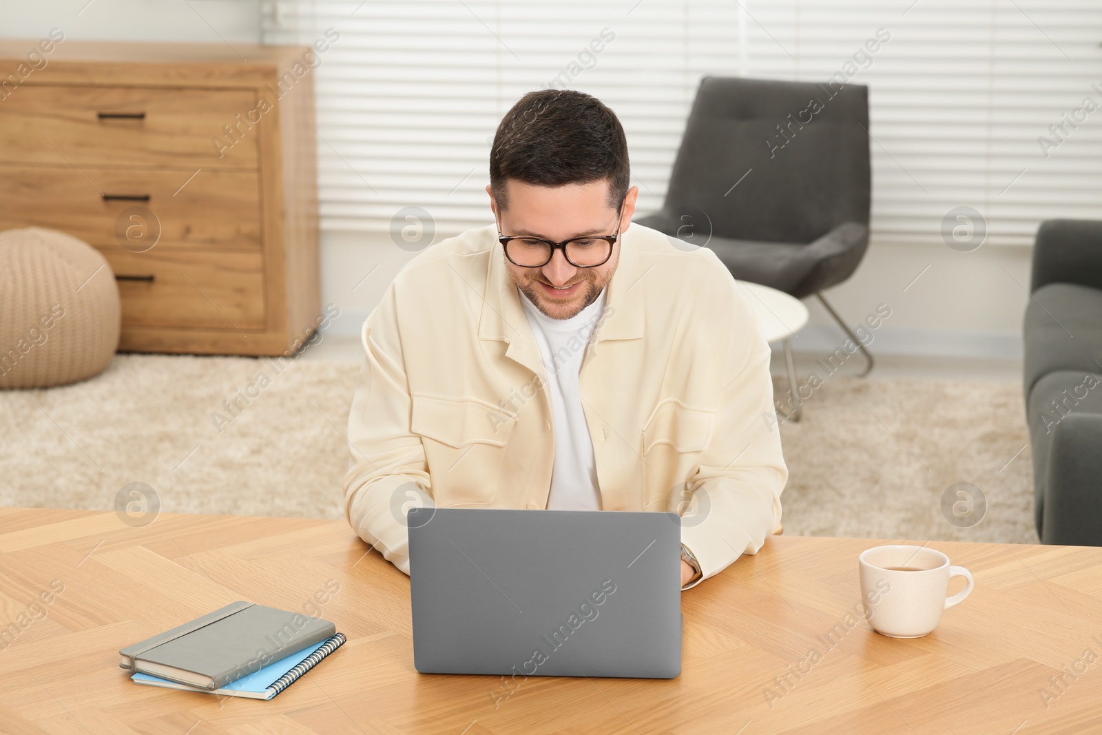 Photo of Man working with laptop at wooden table at home