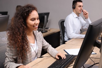 Photo of African American call center operator with headset and her colleague working in modern office