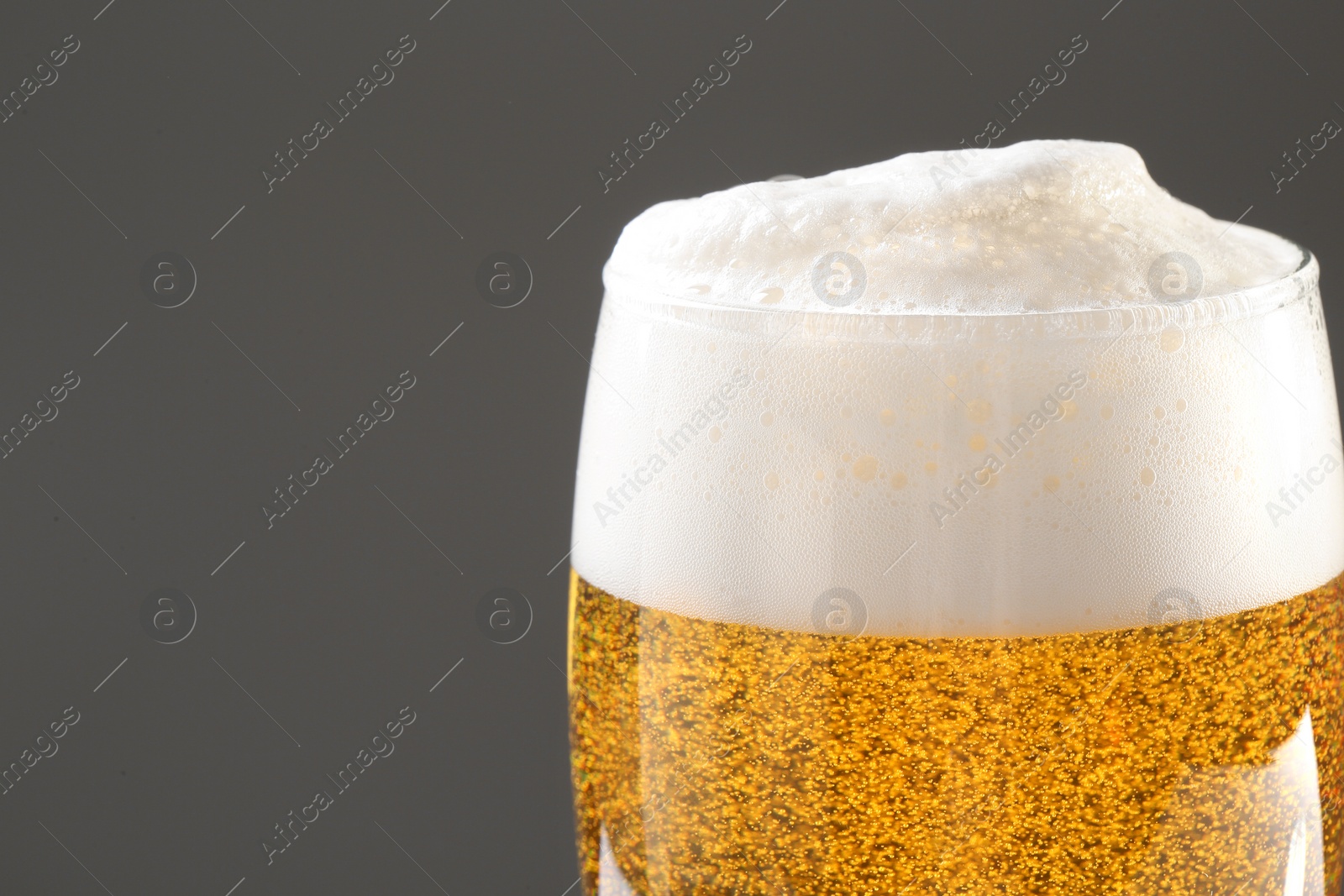 Photo of Glass of tasty beer with foam on color background, closeup