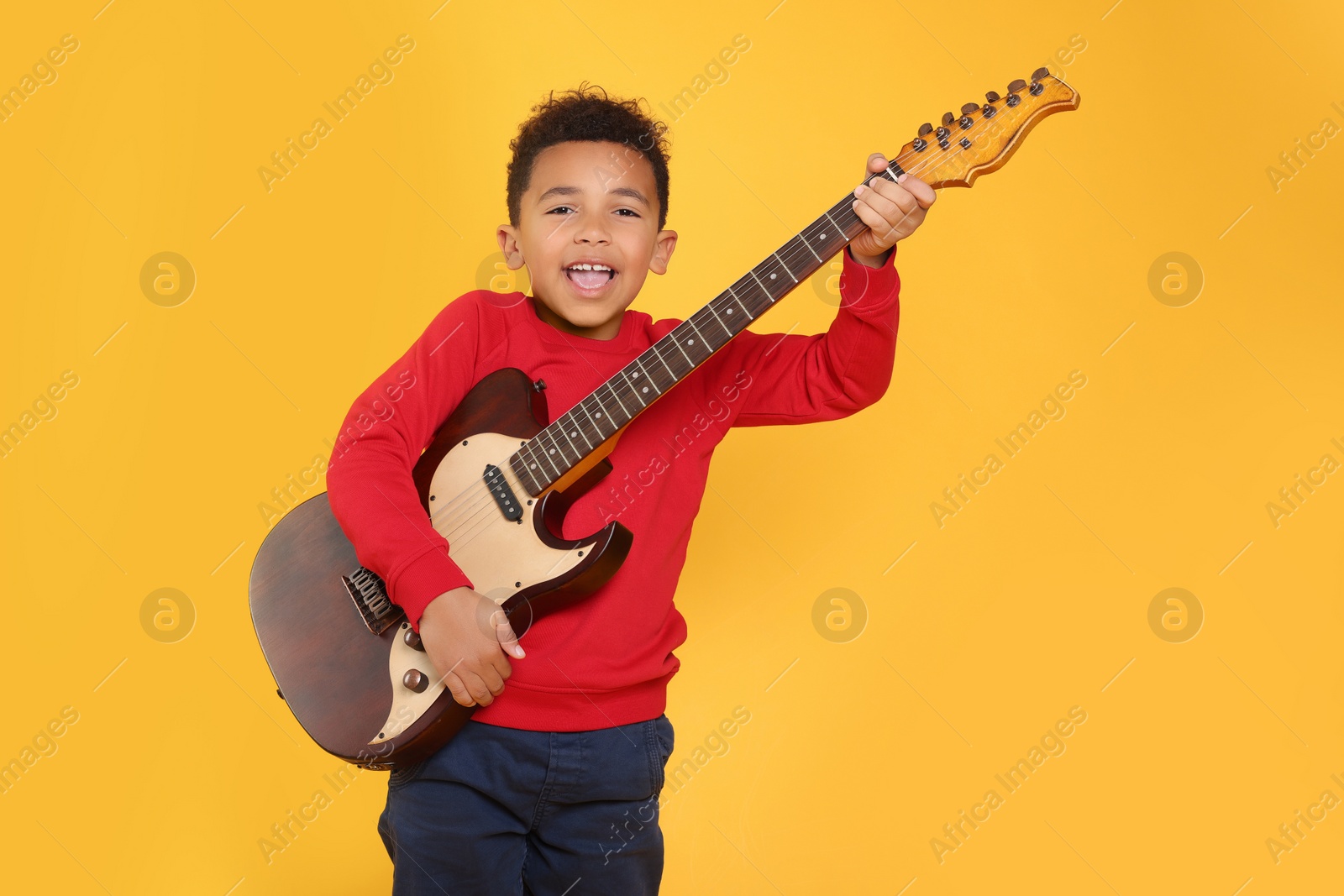 Photo of African-American boy with electric guitar on yellow background