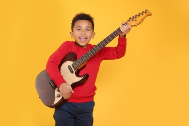 Photo of African-American boy with electric guitar on yellow background