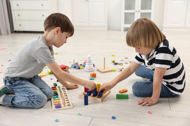 Cute little children playing with wooden blocks on floor indoors