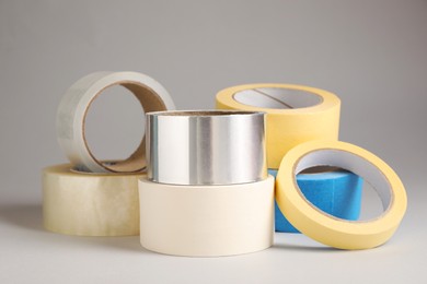 Photo of Many rolls of adhesive tape on light grey background
