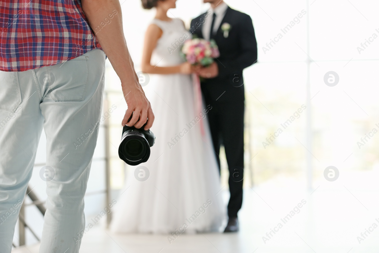 Photo of Professional photographer with camera and wedding couple in studio