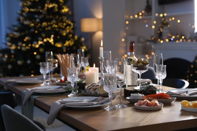 Photo of Christmas table setting with festive decor and dishware in room