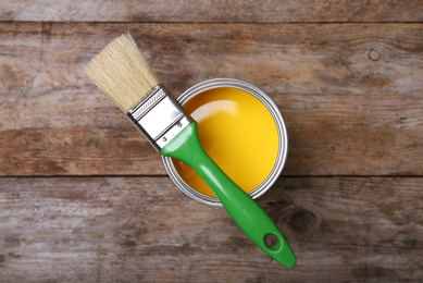 Photo of Paint can and brush on wooden background, top view