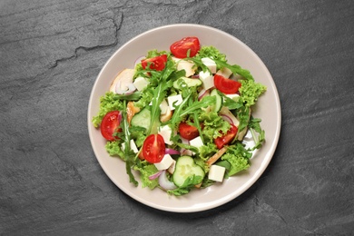 Delicious salad with meat, arugula and vegetables on black table, top view