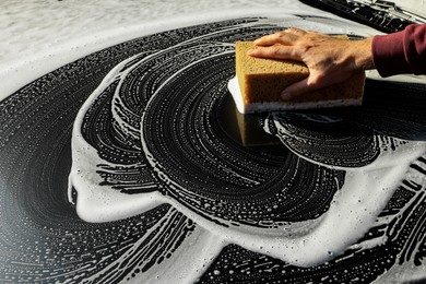 Photo of Worker washing auto with sponge, closeup view