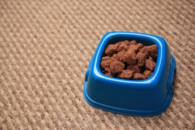 Wet pet food in feeding bowl on soft carpet. Space for text